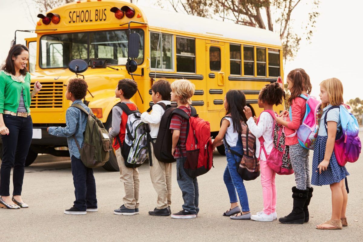 Teacher and a group of elementary school kids at a Make sure you check the weight of your child's backpack